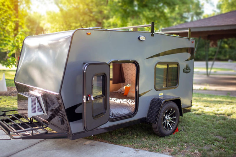 Explore this compact gray RV rental's open door to a cozy bed — photo 1