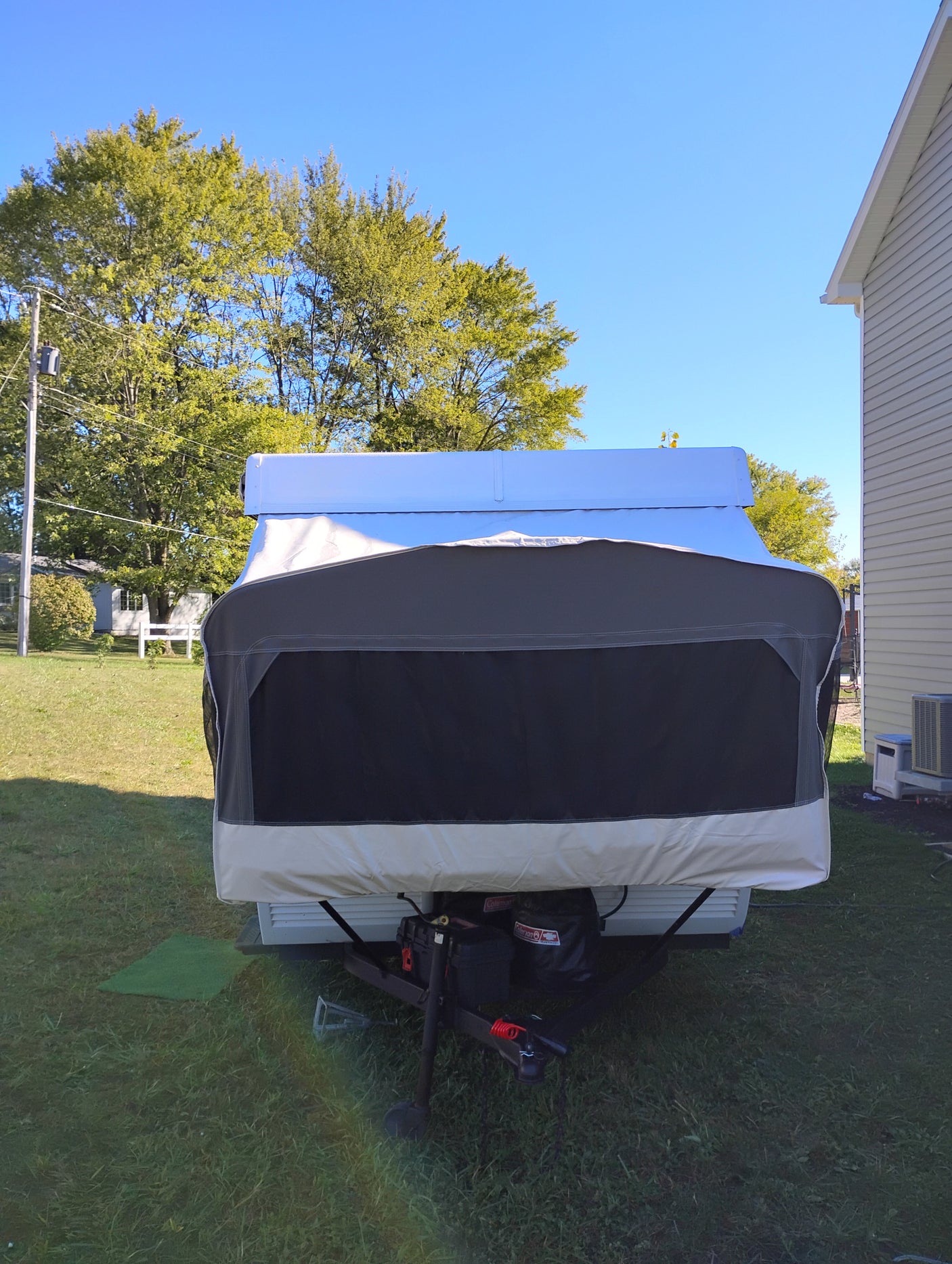 Front view of a covered pop-up camper, ready for an rv rental adventure, parked in a sunny yard.