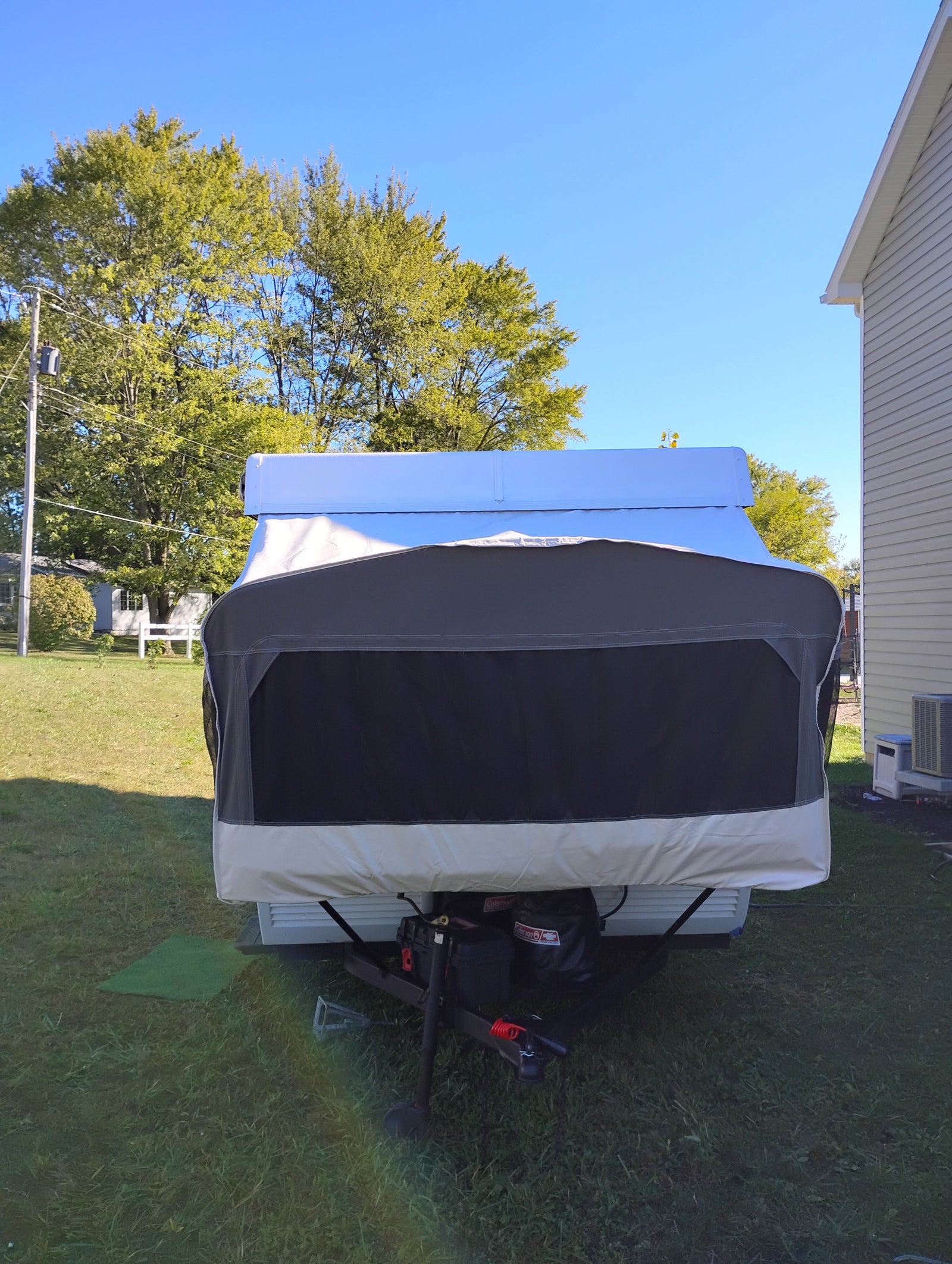 Front view of a covered pop-up camper, ready for an rv rental adventure, parked in a sunny yard.