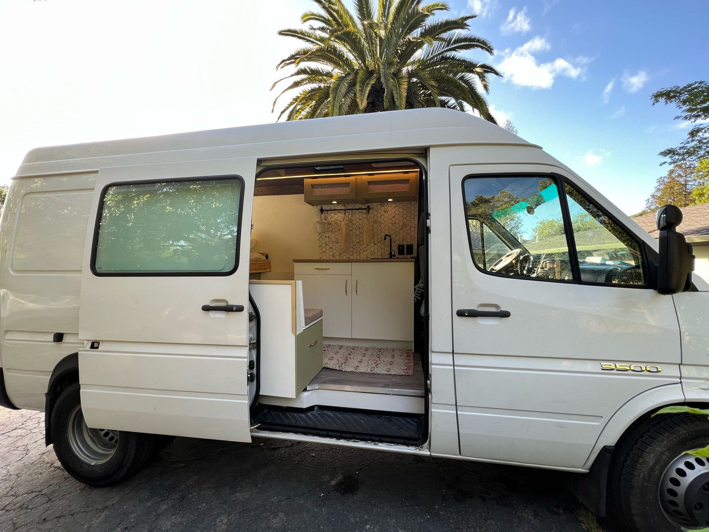 Explore this white Sprinter campervan rv rental, featuring a cozy kitchen & bench seating inside.