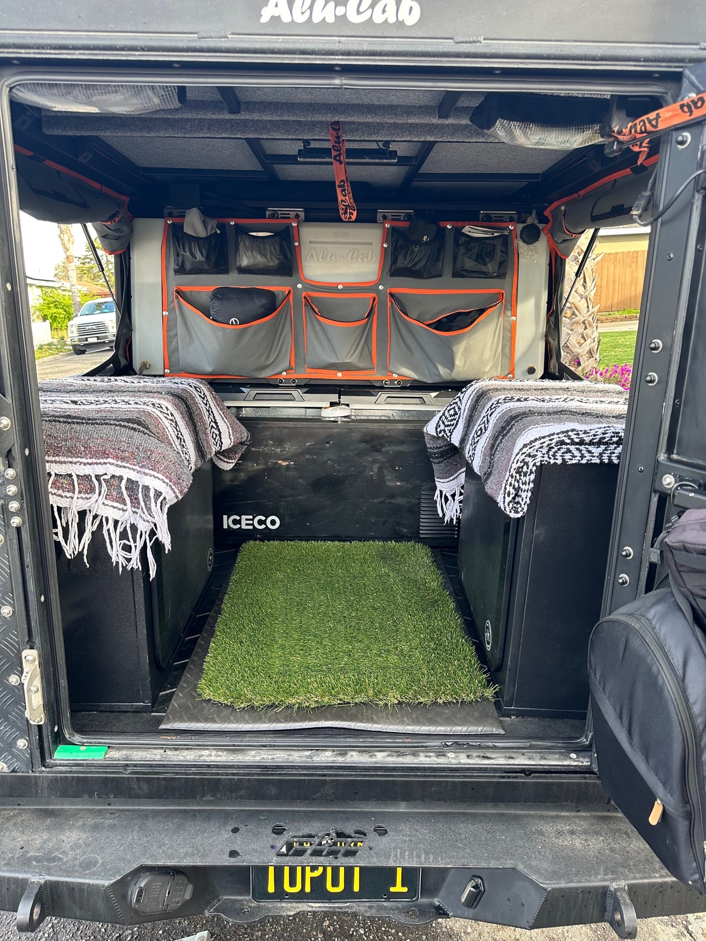 Organized Alu-Cab truck camper interior for an RV rental. Features fridge, storage bags, and cozy blankets. — photo 13