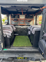 Organized Alu-Cab truck camper interior for an RV rental. Features fridge, storage bags, and cozy blankets.