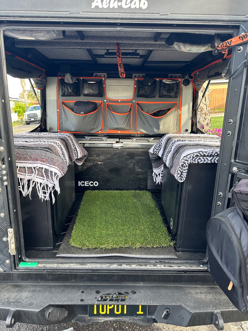 Organized Alu-Cab truck camper interior for an RV rental. Features fridge, storage bags, and cozy blankets. — photo 13