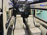 Luxurious rv rental interior with cream quilted leather seats, dark wood paneling, an entertainment screen, and blue ambient lighting.