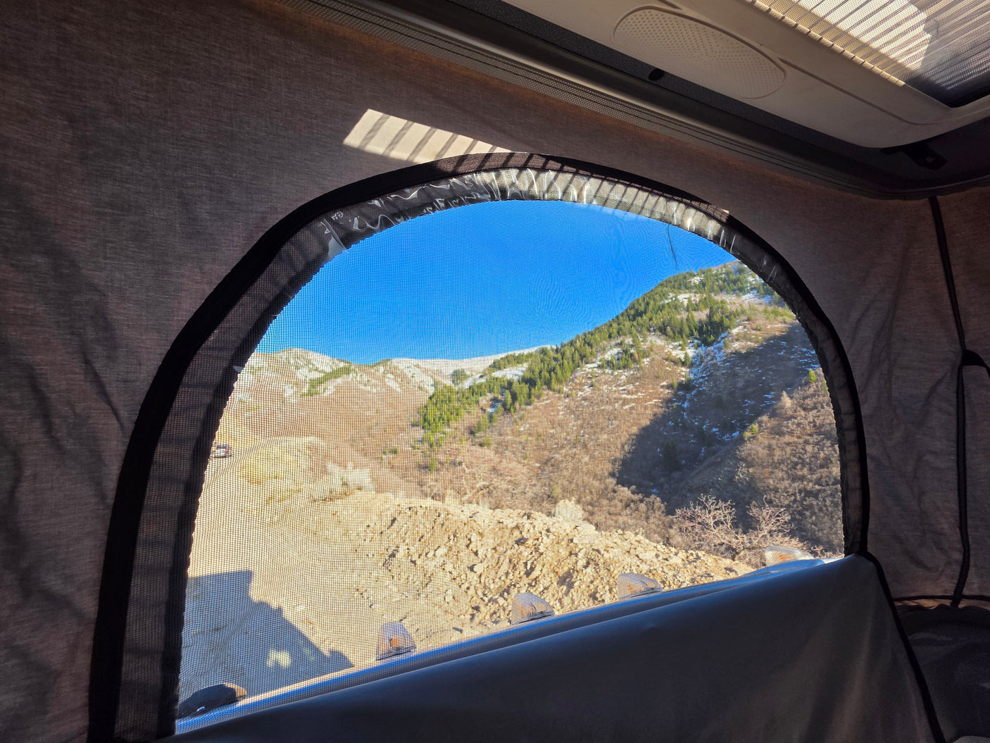 Scenic mountain vista through an RV rental pop-top window, ideal for camping and travel.