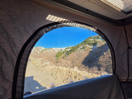 Scenic mountain vista through an RV rental pop-top window, ideal for camping and travel.
