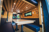 Explore this beautiful RV rental: a wood-clad interior with a dining nook, comfy benches, and ambient lighting.