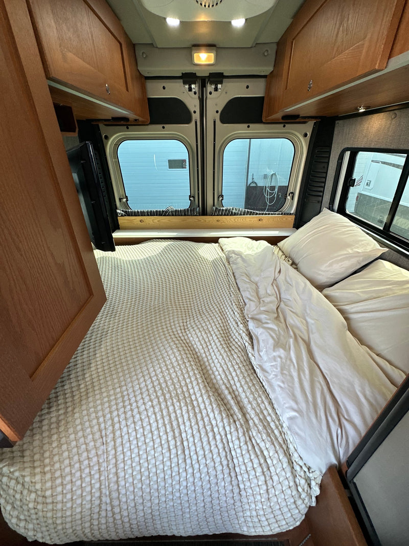  and ceiling fan. Great for mobile living.|A tan RV rental camper van and a silver travel trailer are parked on asphalt under a clear — photo 13