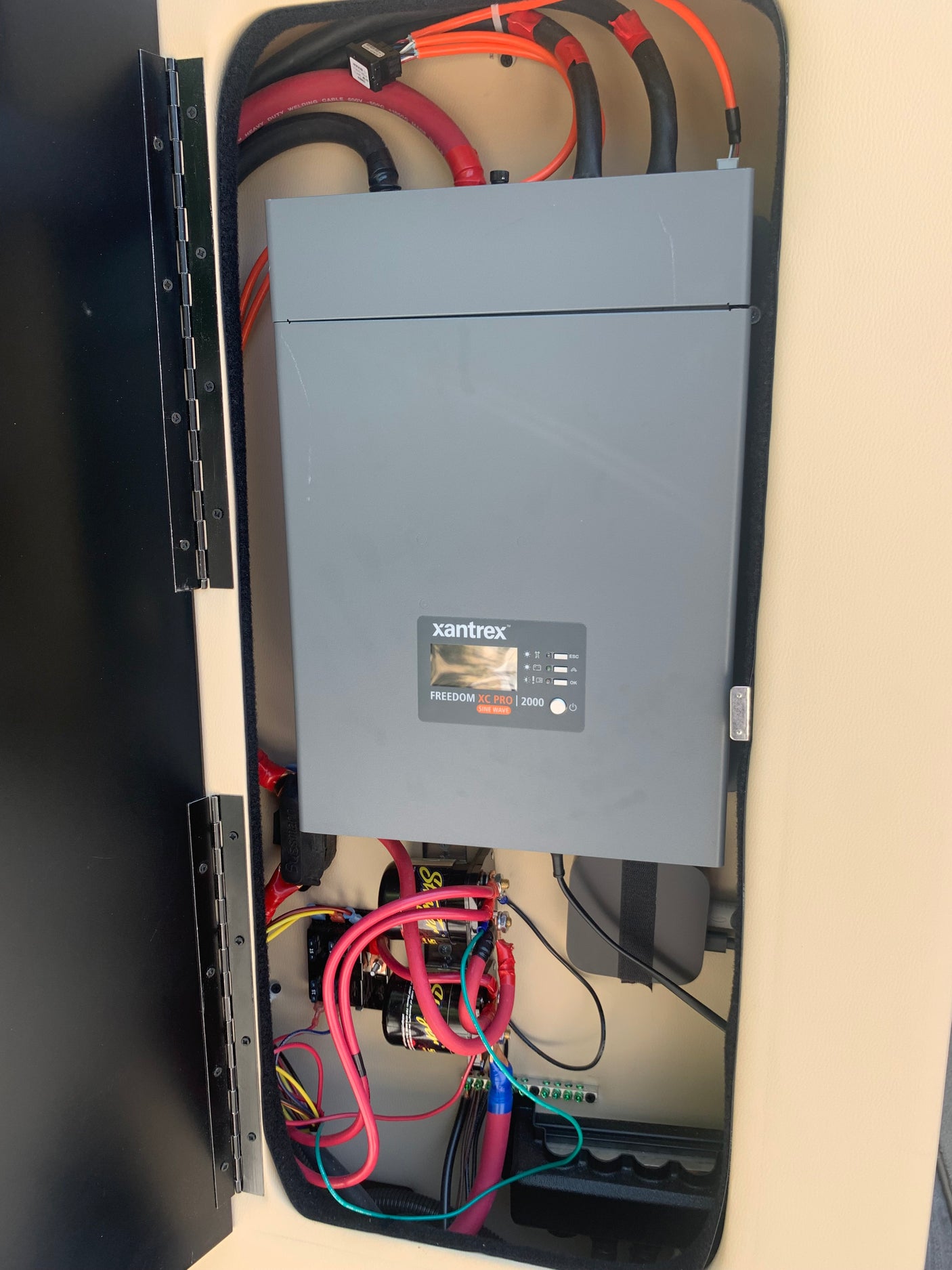 RV rental's power setup: a Xantrex Freedom XC Pro inverter/charger with heavy-duty wiring and electrical components in a service compartment.