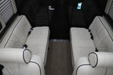 Luxury RV rental interior with opposing plush cream leather seats, quilted design, and dark wood accents.