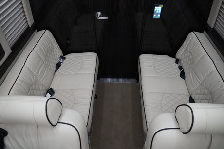 Luxury RV rental interior with opposing plush cream leather seats, quilted design, and dark wood accents.