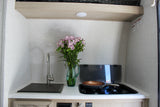 Compact RV rental kitchen featuring a sink, stove, and fresh flowers, ready for your travel adventures.