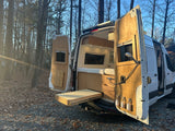 Explore this converted camper van, perfect for RV rental adventures. Custom wood interior and outdoor shower for van life.