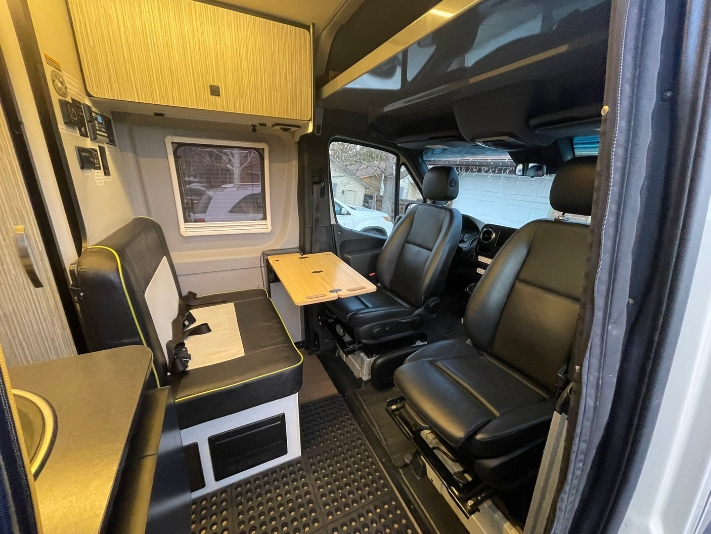 This RV rental features swivel front seats, a compact dinette with a wooden table, and practical overhead storage for travel.