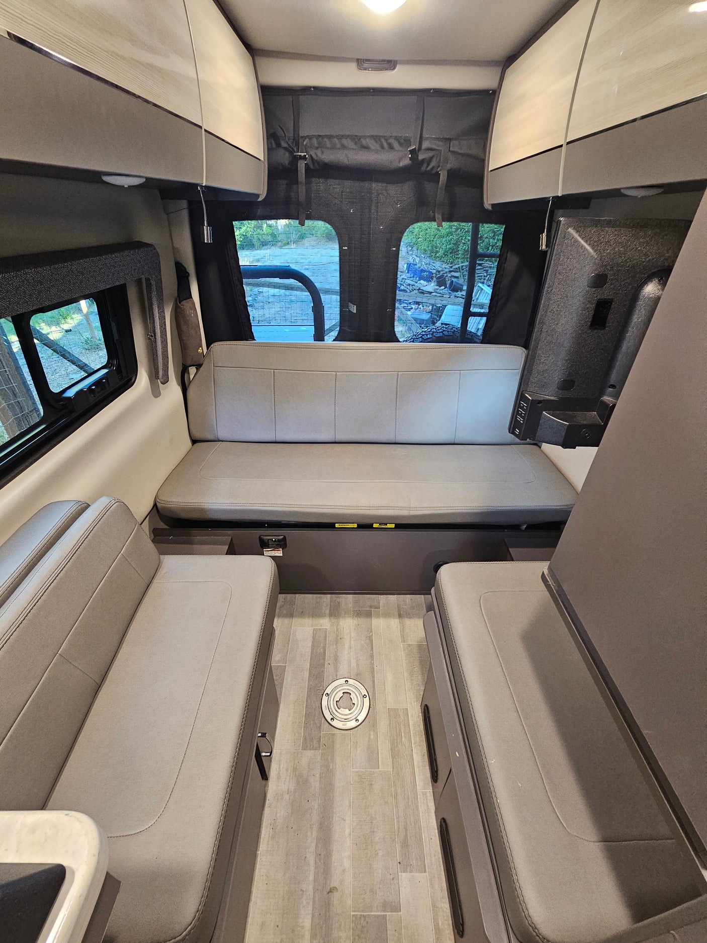 RV rental interior: light-colored seating, overhead cabinets, and a flat-screen TV in a spacious mobile living area.
