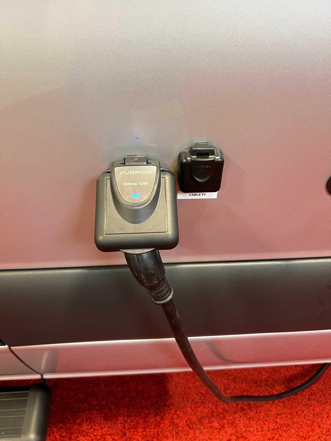 Close-up of an RV rental's electrical hookup (Furrion 30A 125V) and Cable TV inlet, ready for use.