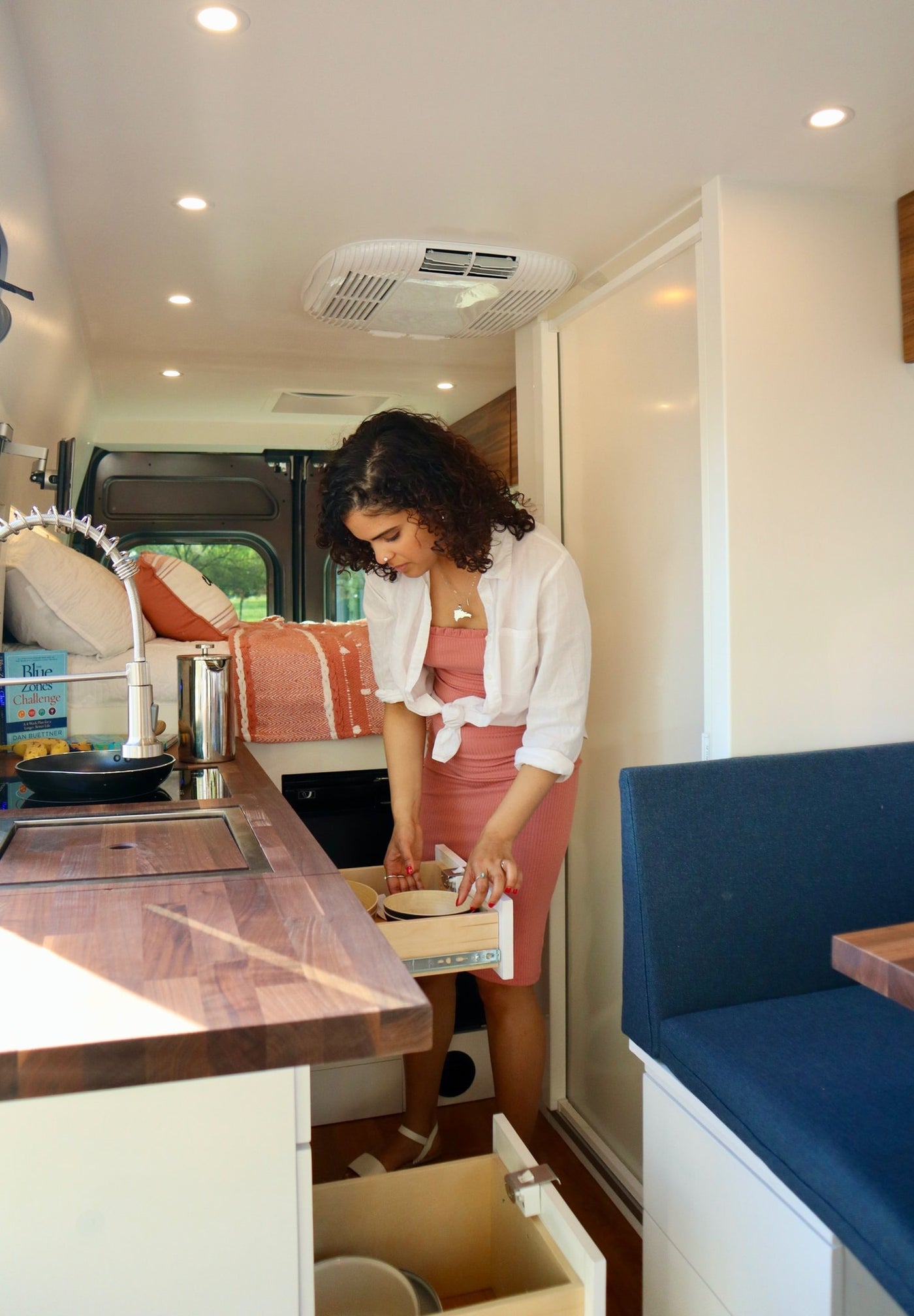  ready for your RV rental journey. Parked by a dark wall.|Inside an RV rental van: custom storage below a raised bed — photo 3