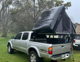 Toyota Tacoma with iKamper rooftop tent ready for camping in misty woods, a unique RV rental experience.