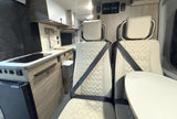 Compact rv rental interior featuring a functional kitchen, comfortable dual seating, and an accessible solar charge controller.