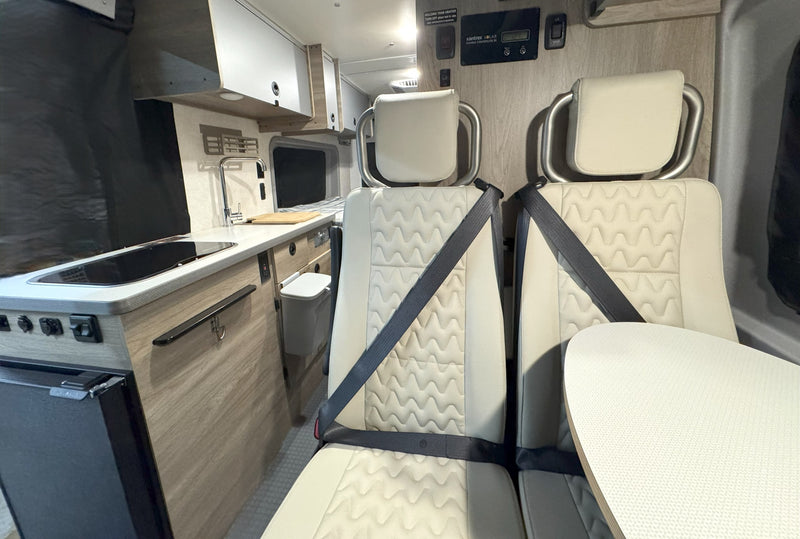 Compact rv rental interior featuring a functional kitchen, comfortable dual seating, and an accessible solar charge controller. — photo 18
