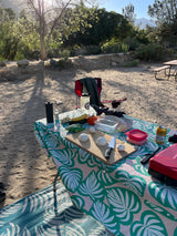 RV rental adventure: Fresh veggies, knife, and cutting board ready for campsite cooking on a colorful tablecloth.