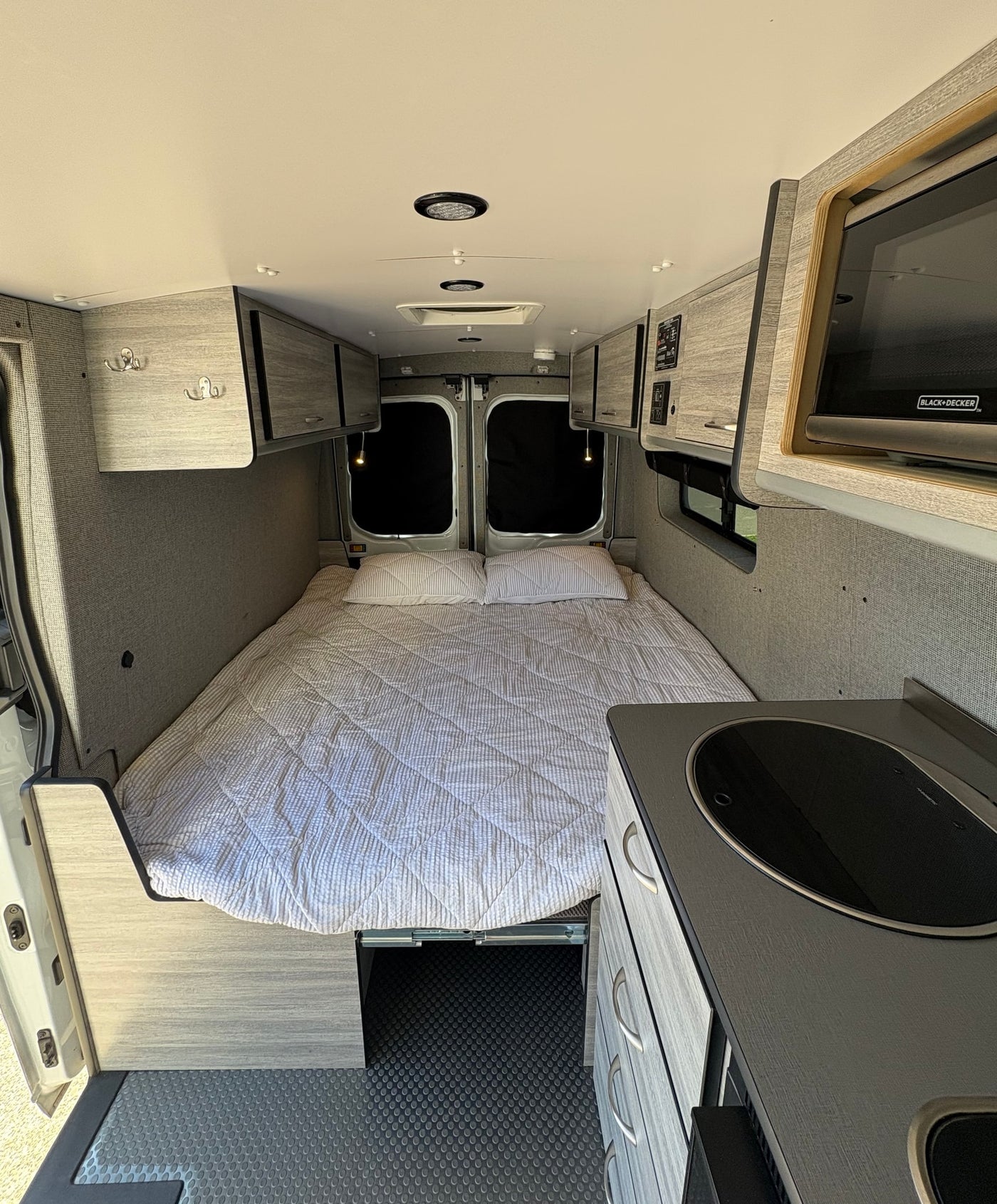 Spacious camper van interior, perfect for an RV rental adventure. Features a comfortable bed, kitchenette, and ample storage. — photo 2