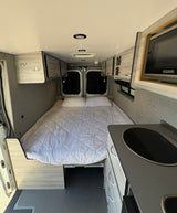 Spacious camper van interior, perfect for an RV rental adventure. Features a comfortable bed, kitchenette, and ample storage.