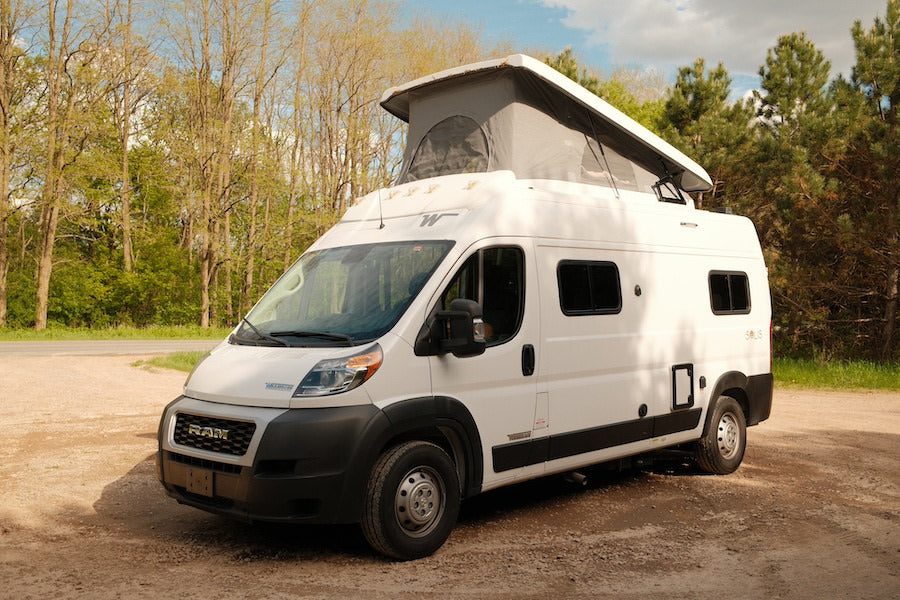 White pop-top camper van, an ideal rv rental, parked on a rustic path, ready for your next outdoor adventure.
