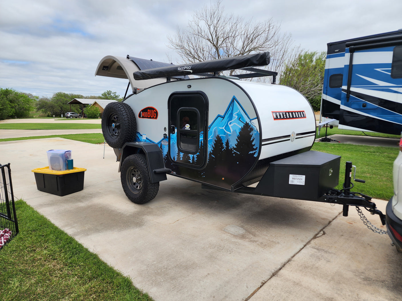 Stylish teardrop camper with mountain graphics & solar, parked at an RV site. Ideal for an RV rental outdoor adventure.