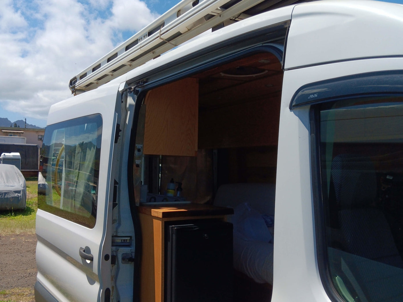 Side view of an RV rental camper van with its door open, showcasing a compact interior with kitchen area and bed. — photo 4