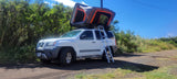 White Nissan Xterra SUV with a deployed rooftop tent and ladder. This RV rental is ready for outdoor adventure.