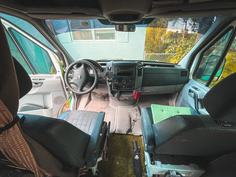 Inside an RV rental camper van, revealing the cockpit, dashboard, and front seats from a rear perspective.