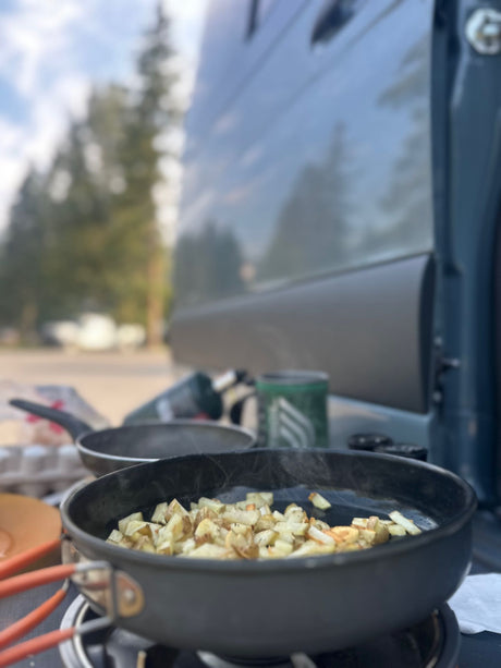 Sizzling home fries on a portable stove, cooking outside an RV rental. Perfect for a delicious camping breakfast.