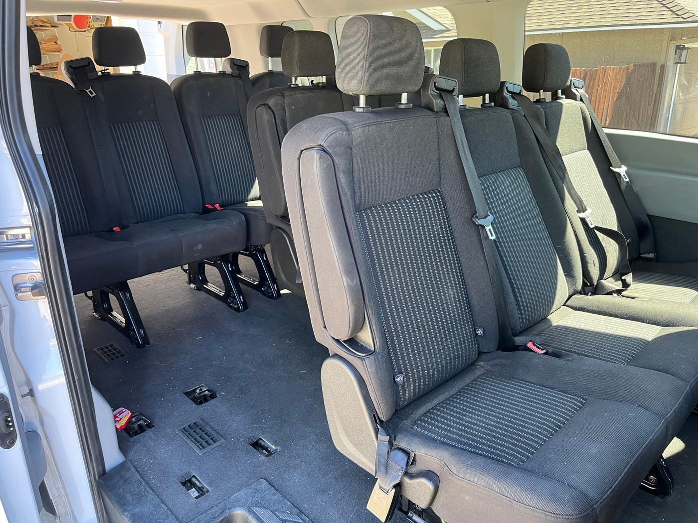 Inside an RV rental, rows of dark fabric passenger seats with seatbelts, ready for group travel. — photo 2