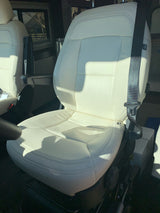Bright cream captain's chair with black seatbelt and armrest inside an RV rental. Ready for travel comfort.