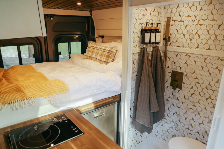 Experience comfort in this modern RV rental! Features include a cozy bed, kitchen, and beautiful tiled shower.