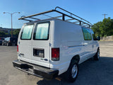 A white Ford E-350 van with a roof rack and insulated rear windows, seen from behind. Great for rv rental.