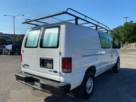 A white Ford E-350 van with a roof rack and insulated rear windows, seen from behind. Great for rv rental.