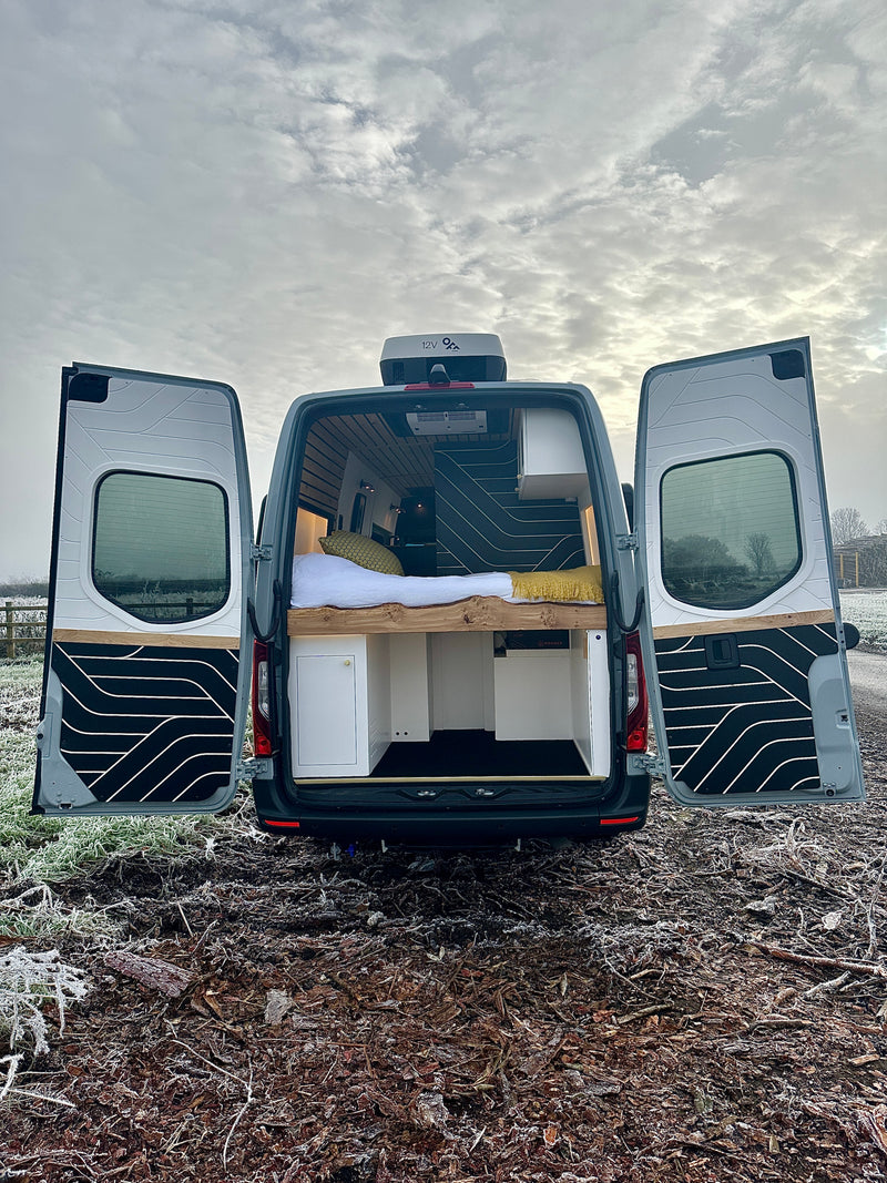 Open rear doors of a custom campervan reveal a cozy bed & storage. Perfect for RV rental adventures in frosty landscapes. — photo 16