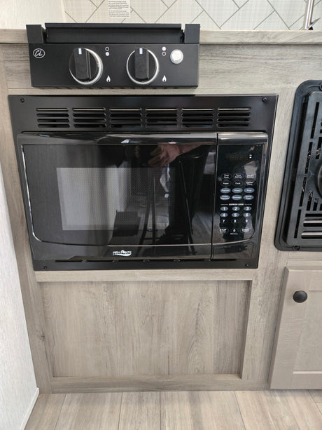 An rv rental kitchen with a built-in High Pointe microwave and two-burner cooktop, integrated into light wood cabinetry.