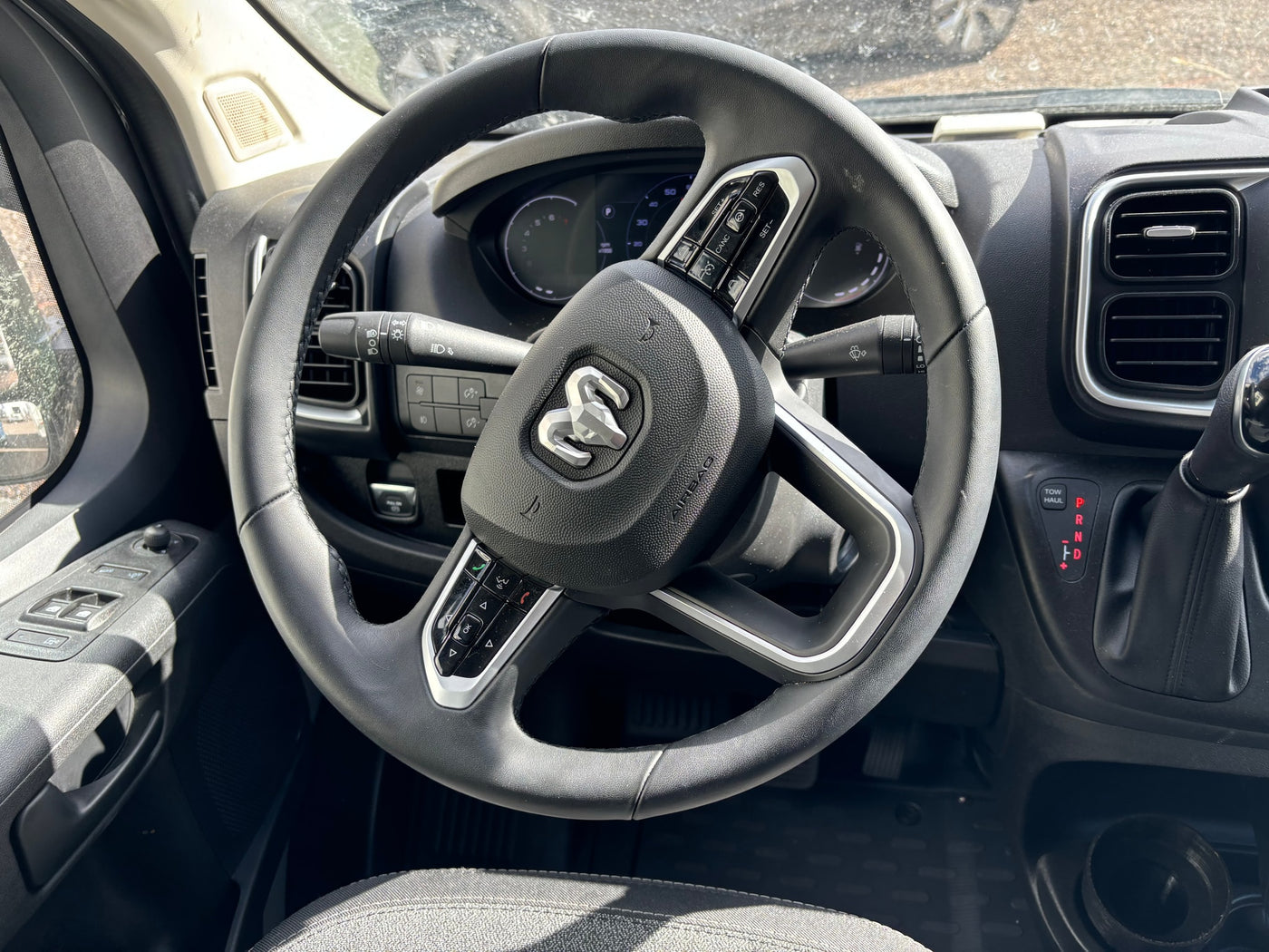 RV rental interior: close-up of the steering wheel with Ram logo and controls, revealing the dashboard and gear shifter. — photo 11