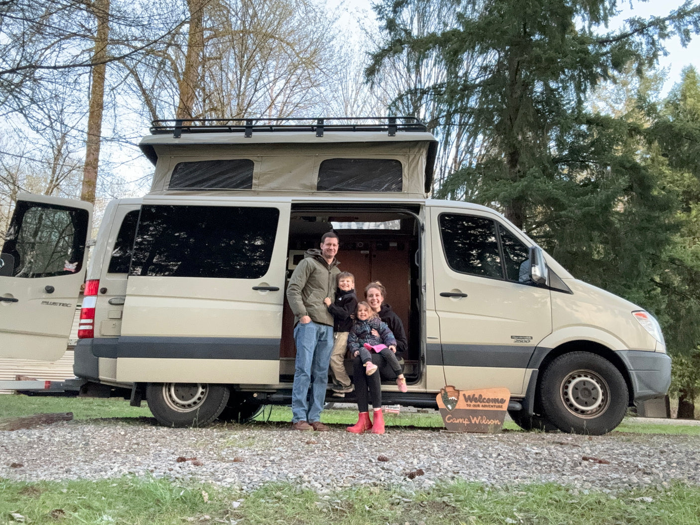 Happy family with their pop-top RV rental, a tan camper van, ready for adventures.