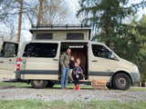 Happy family with their pop-top RV rental, a tan camper van, ready for adventures.