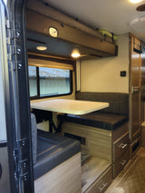 Inside this rv rental: a comfy dinette, an overhead bunk bed, and storage solutions for convenient travels.
