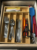 RV rental kitchen drawer with organized utensils: forks, spoons, knives, spatula, can opener, shears in a bamboo organizer.