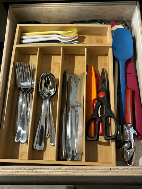RV rental kitchen drawer with organized utensils: forks, spoons, knives, spatula, can opener, shears in a bamboo organizer.