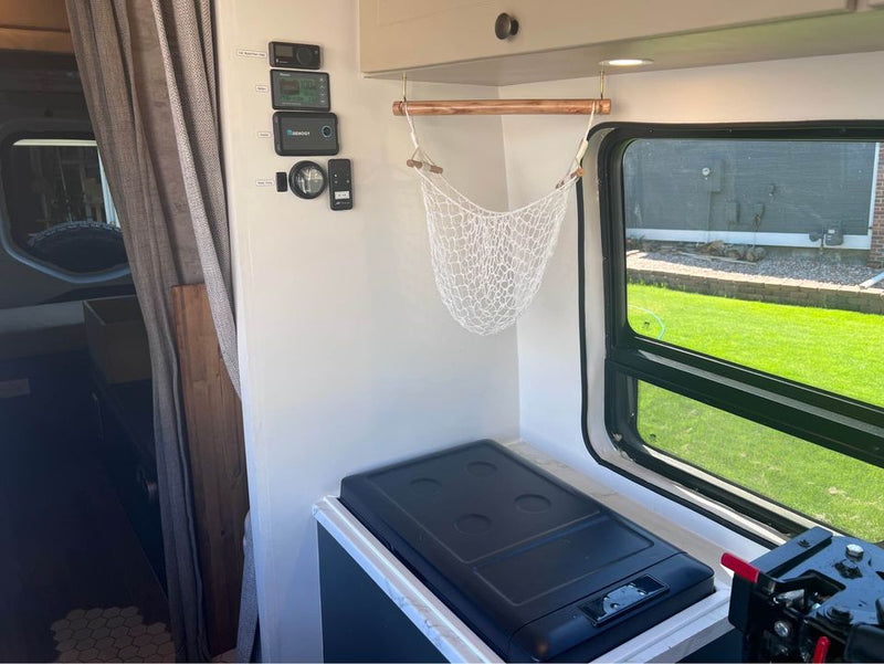  and herringbone backsplash. Rainy outside.|Camper van rental interior: two black seats — photo 5