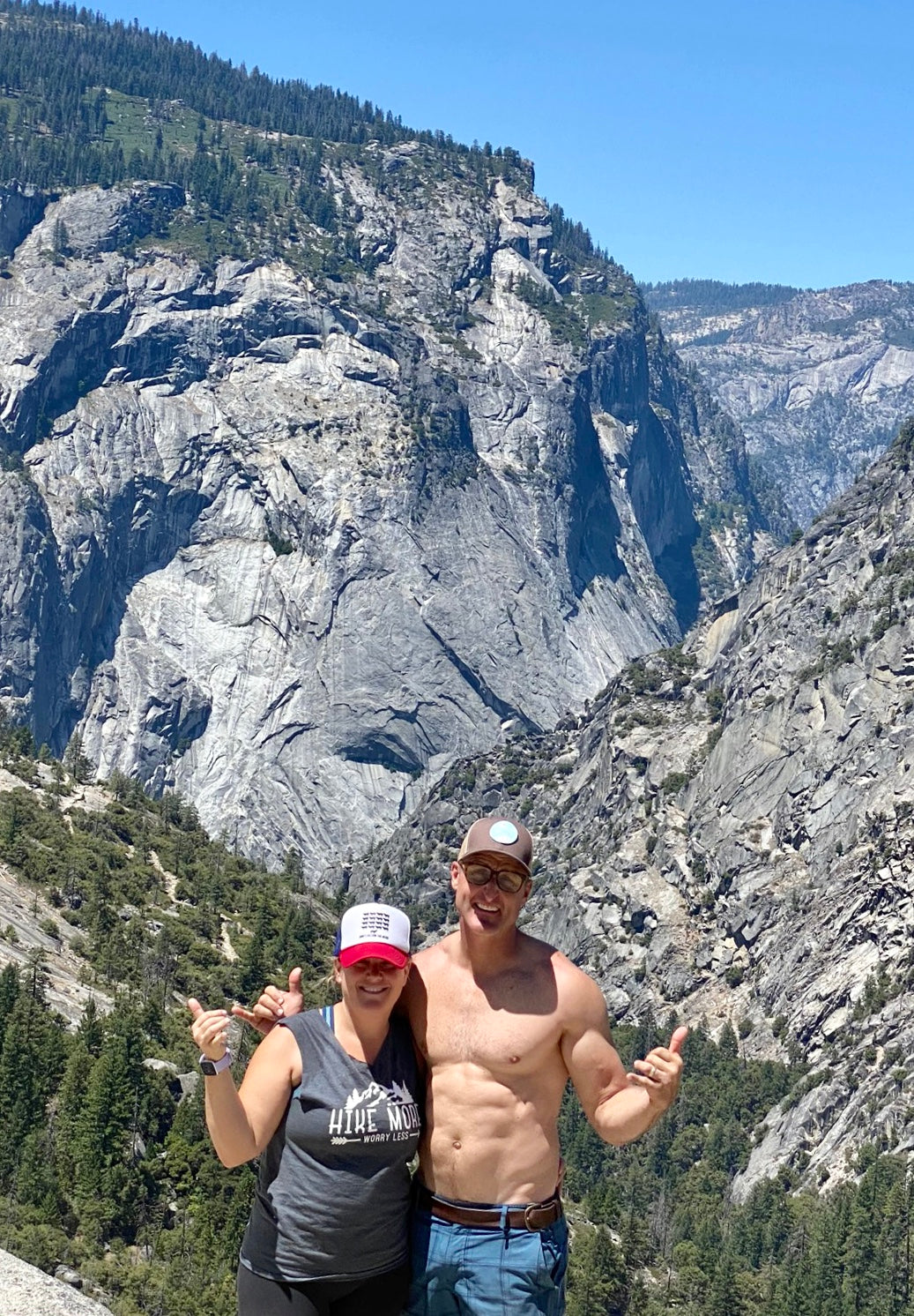Smiling adventurers showcase vast granite cliffs. An RV rental enhances trips to breathtaking national parks like this for epic hikes.
