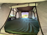 Spacious RV rental tent interior with a large green mattress and views, ideal for comfortable outdoor adventures.