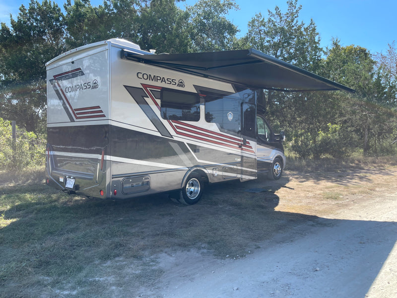 Enjoy the outdoors! This Thor Compass AWD RV rental is parked with its awning extended under a clear sky. — photo 9